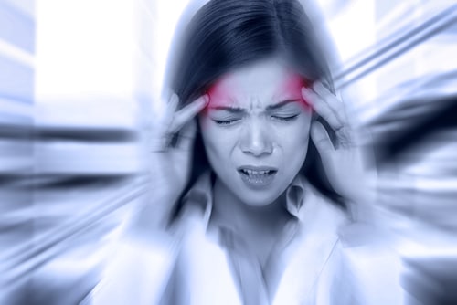 woman holding hands to head, blurred background