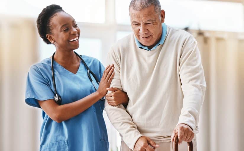 A doctor in blue scrubs helping an elderly man with physical therapy.