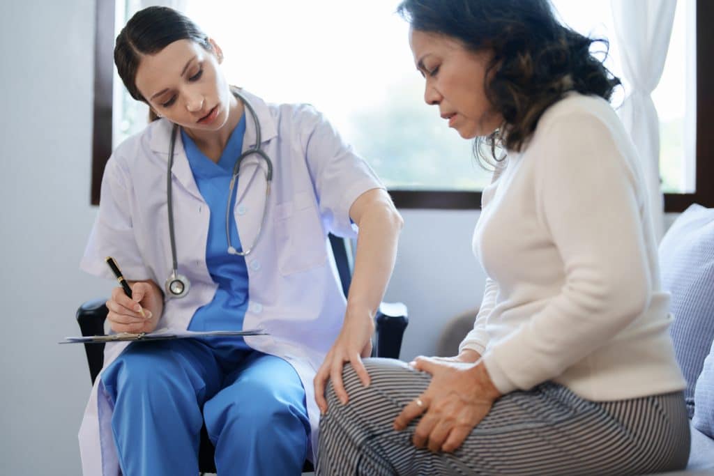 A doctor examining a patient’s knee.