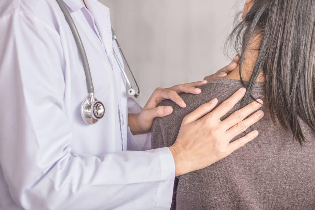 Female doctor examining a patient suffering from neck and shoulder pain stock photo