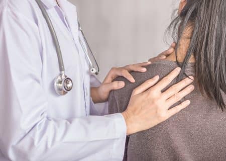 Female doctor examining a patient suffering from neck and shoulder pain stock photo