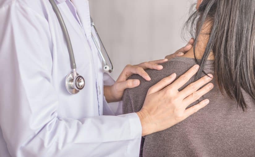 Female doctor examining a patient suffering from neck and shoulder pain stock photo